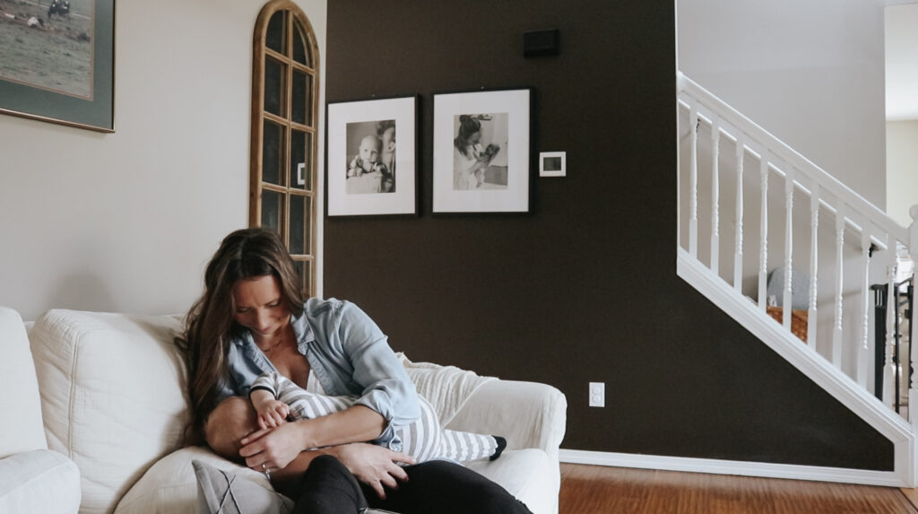Christian homemaker sits on couch playing with her baby